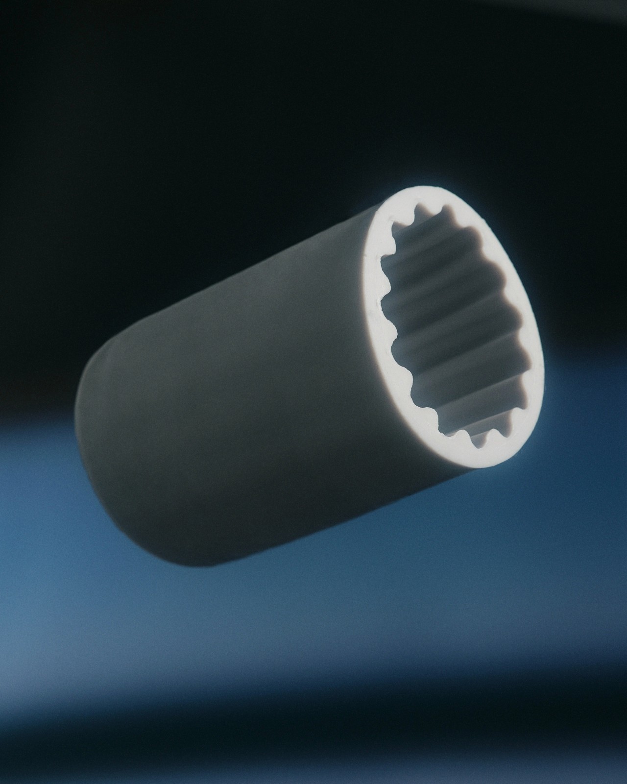 A cylindrical object with a textured inner surface floating against a dark background.