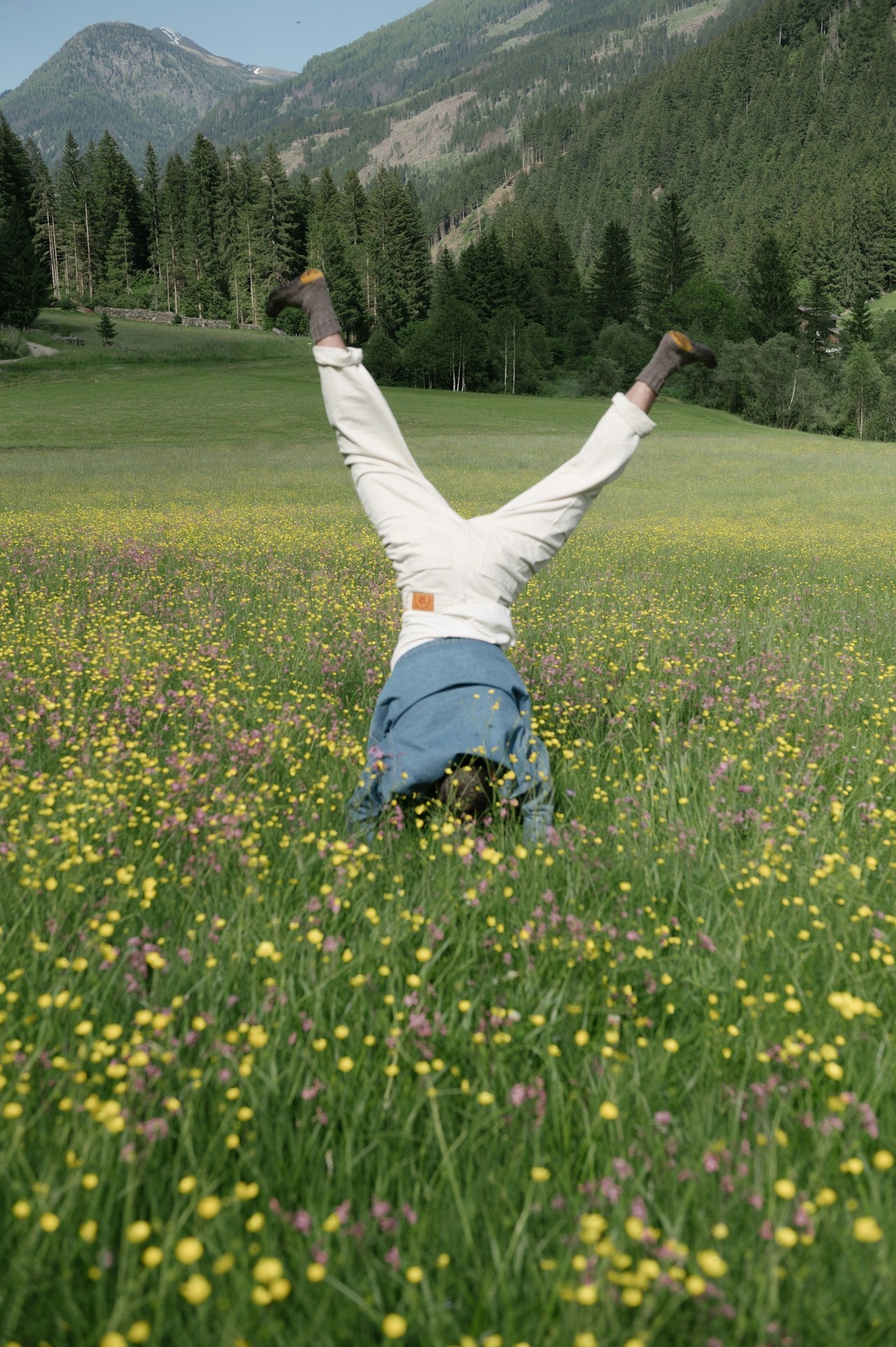 A gymnast performing a flip on a grassy green field.