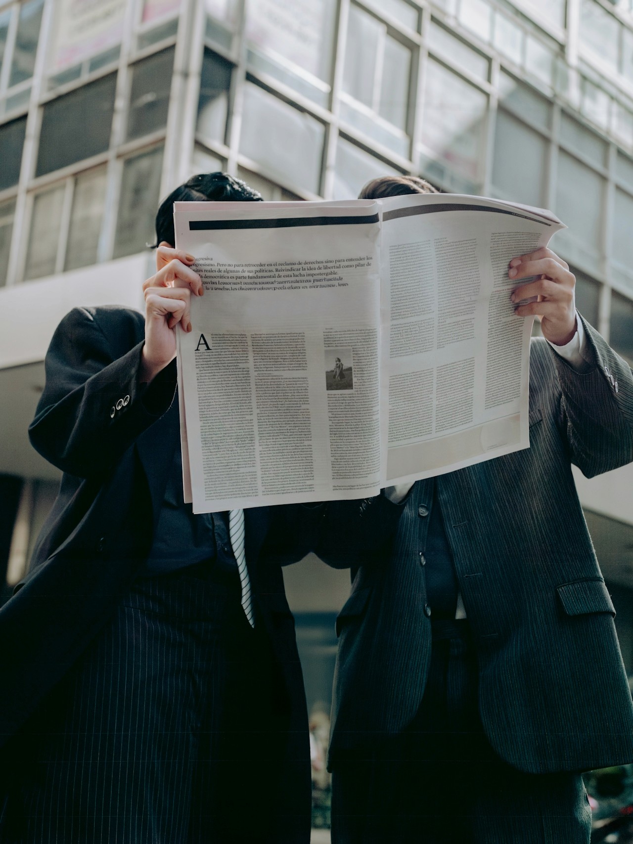 Two friends reading a newspaper together.