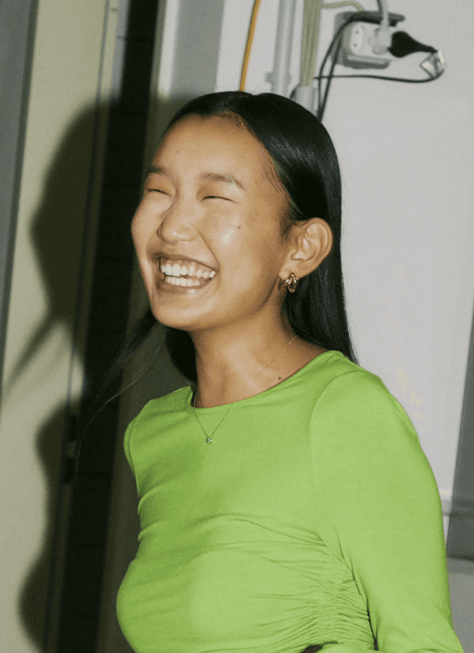 A woman smiling brightly while wearing a green top.