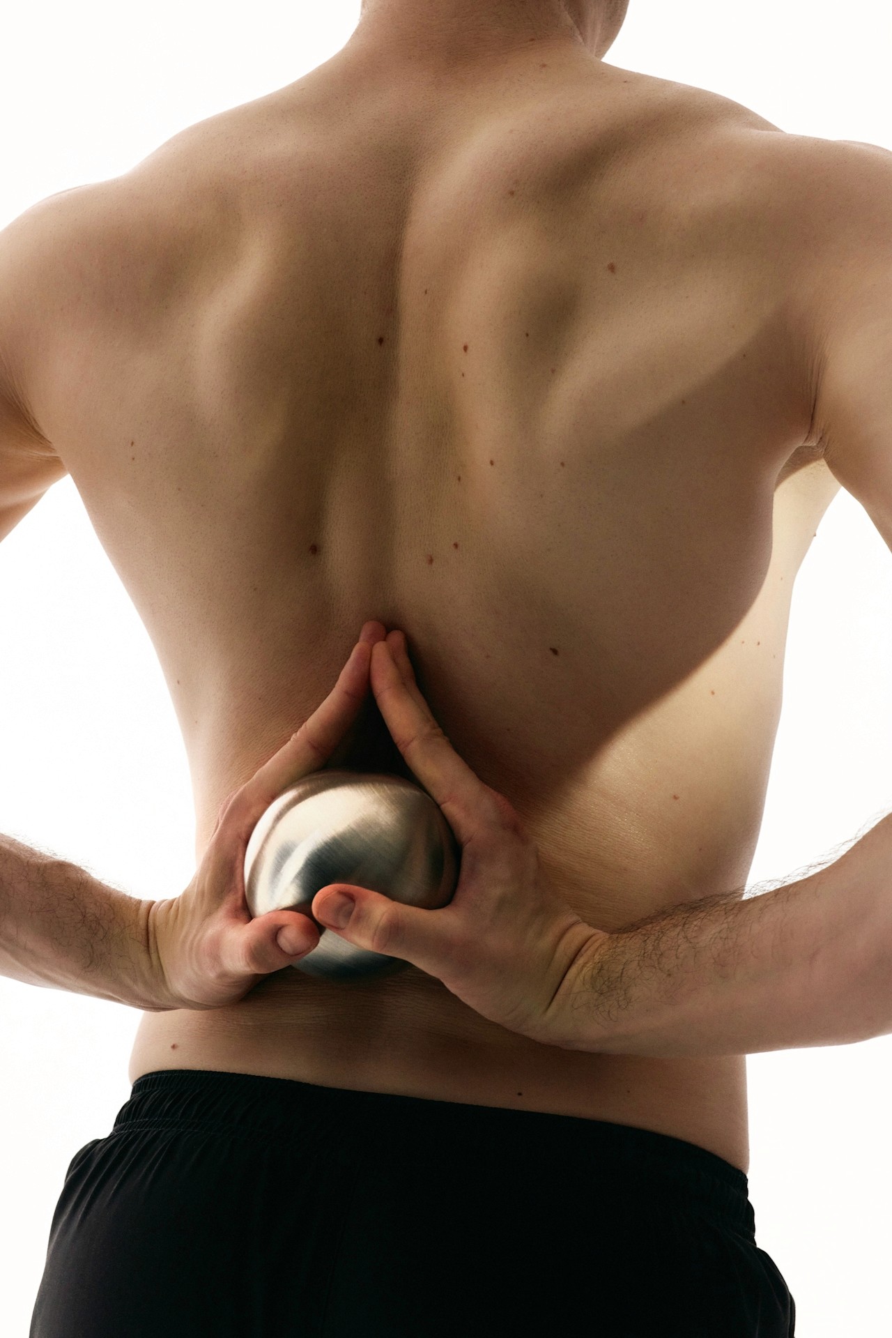A yoga pose holding a steel ball behind the back.