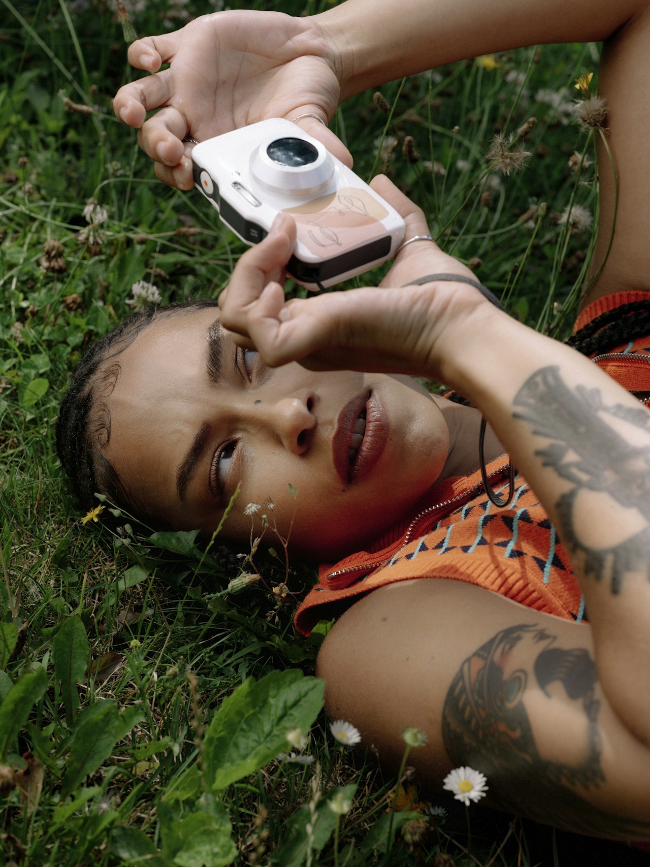 A woman capturing a photo with her camera while lying on the floor.