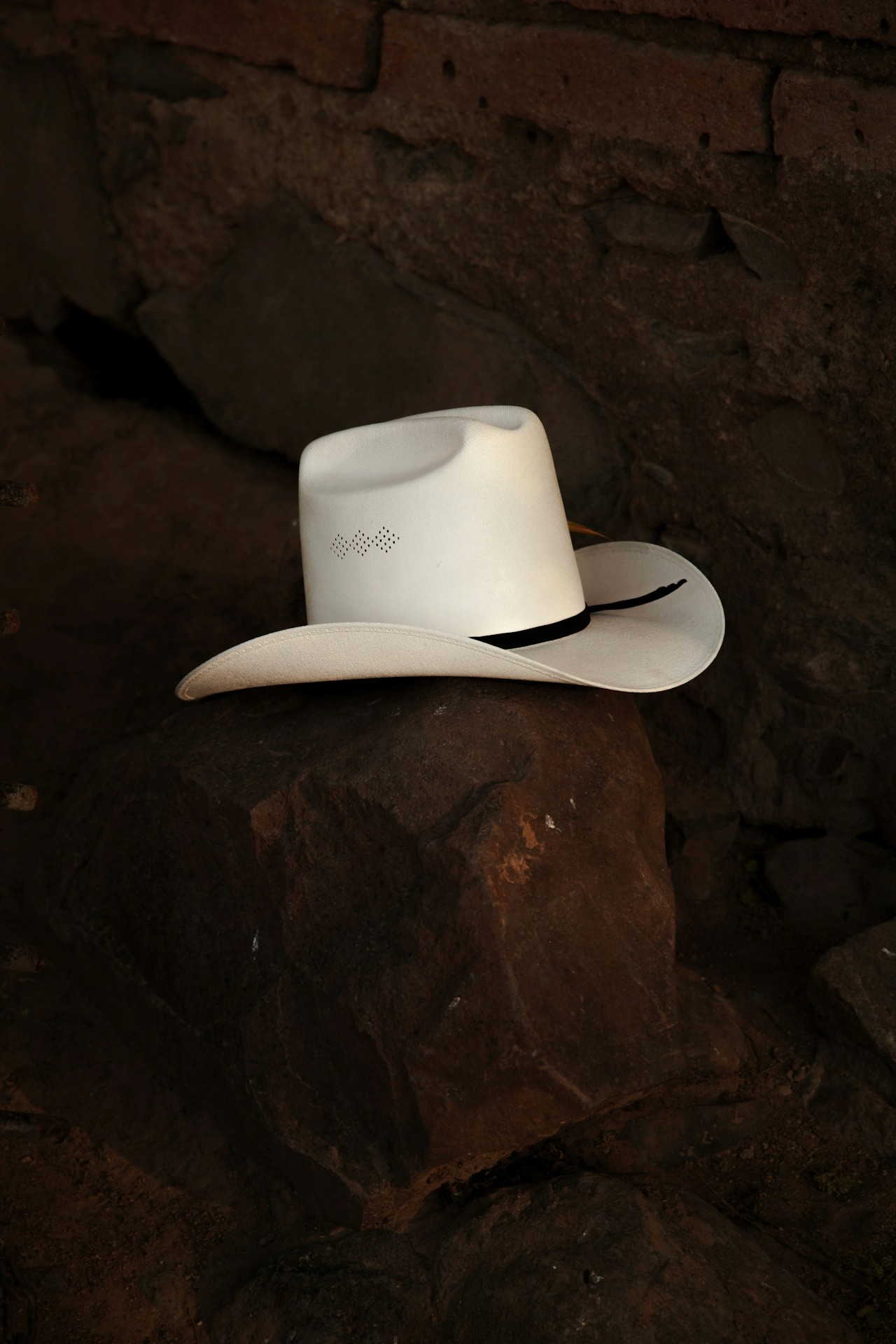 A white cowboy hat resting on dark rocks.