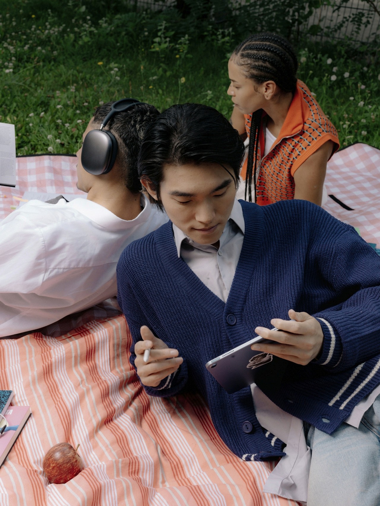 Three friends enjoying work while sitting in a picnic setup.