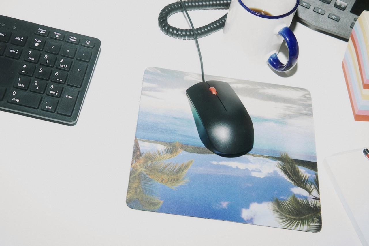 A desk setup with a mouse, keyboard, phone, and coffee cup.