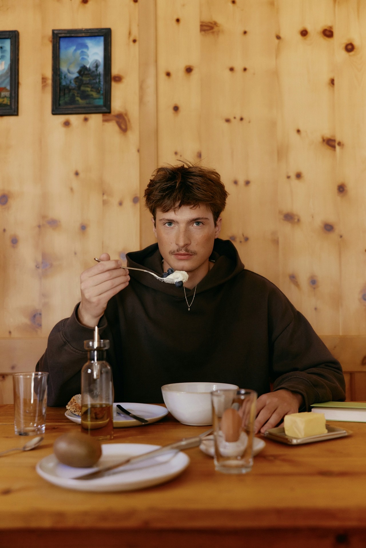 A man sitting at a table while eating, photographed in a casual interior.