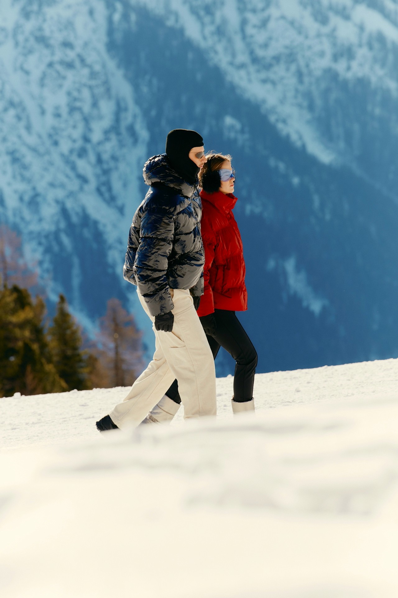 A couple walking together on a snow-covered mountain.