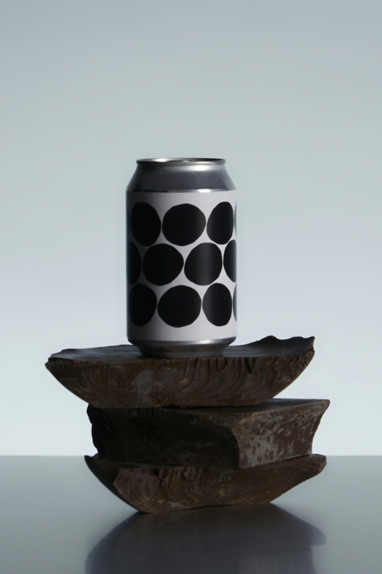 A minimalist composition of a patterned can balanced on stacked stones.