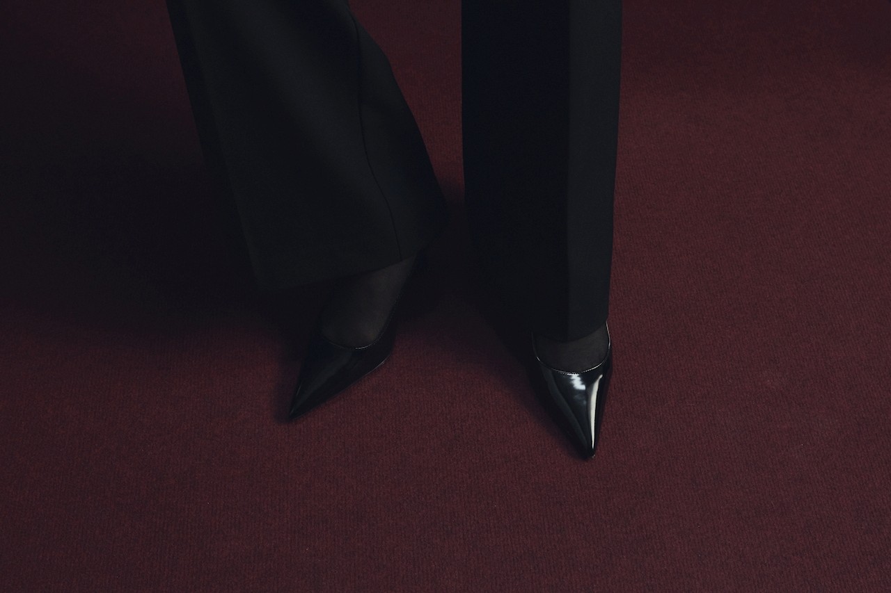 Black women’s shoes against a maroon carpet background.