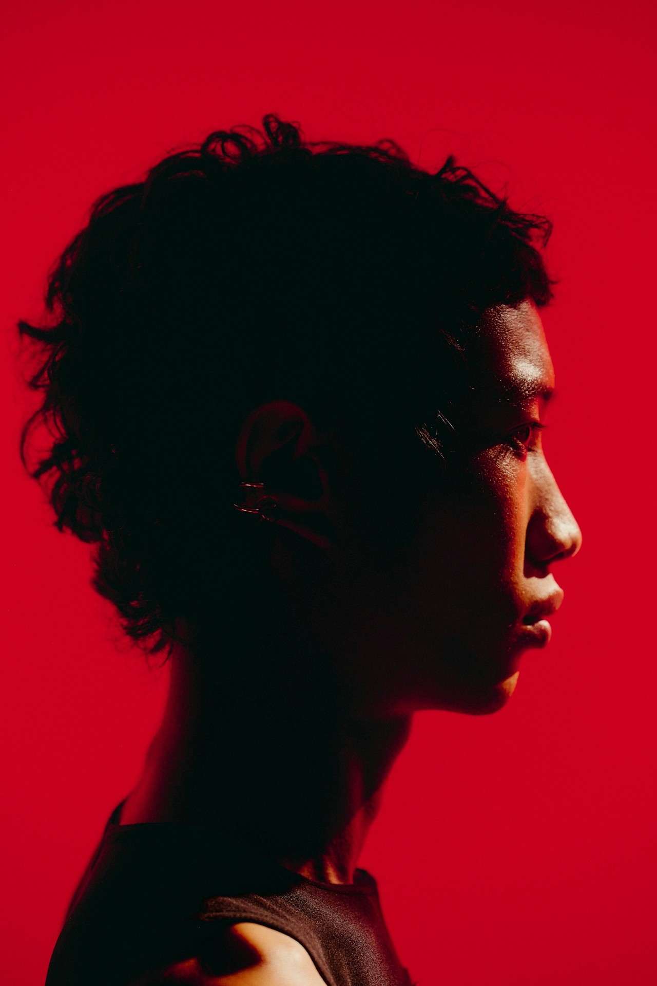 A side-profile portrait of a person against a red background.