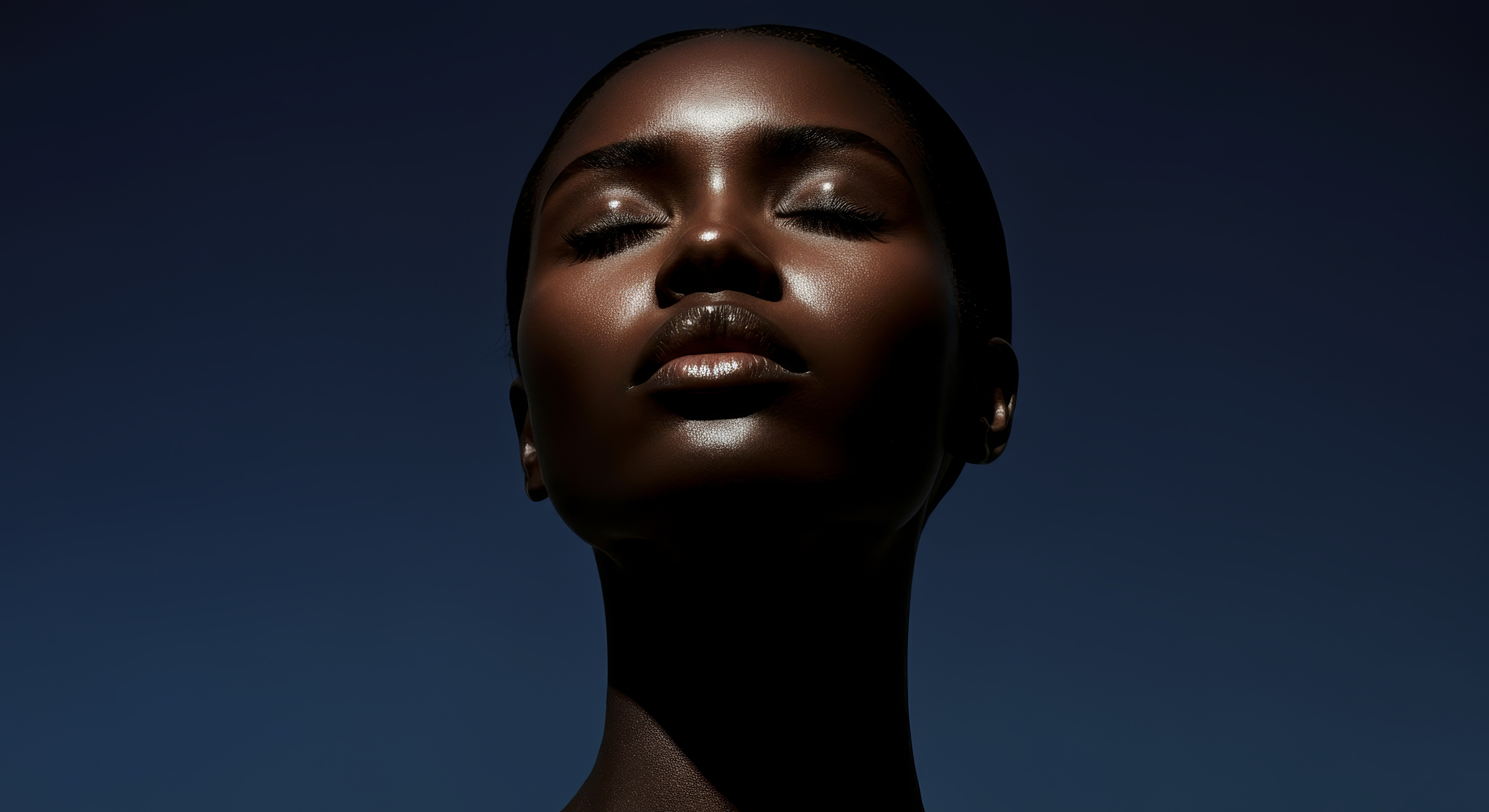 A captivating close-up portrait of a woman with deep, radiant skin and closed eyes, highlighting the luminous quality of her complexion. The subtle sheen on her skin emphasizes beauty, health, and premium product quality. This image is perfect for showcasing high-end beauty, cosmetic, or skincare products on a **Liqua Premium Ecommerce template**, enhancing the visual appeal and perceived value of any luxury brand.