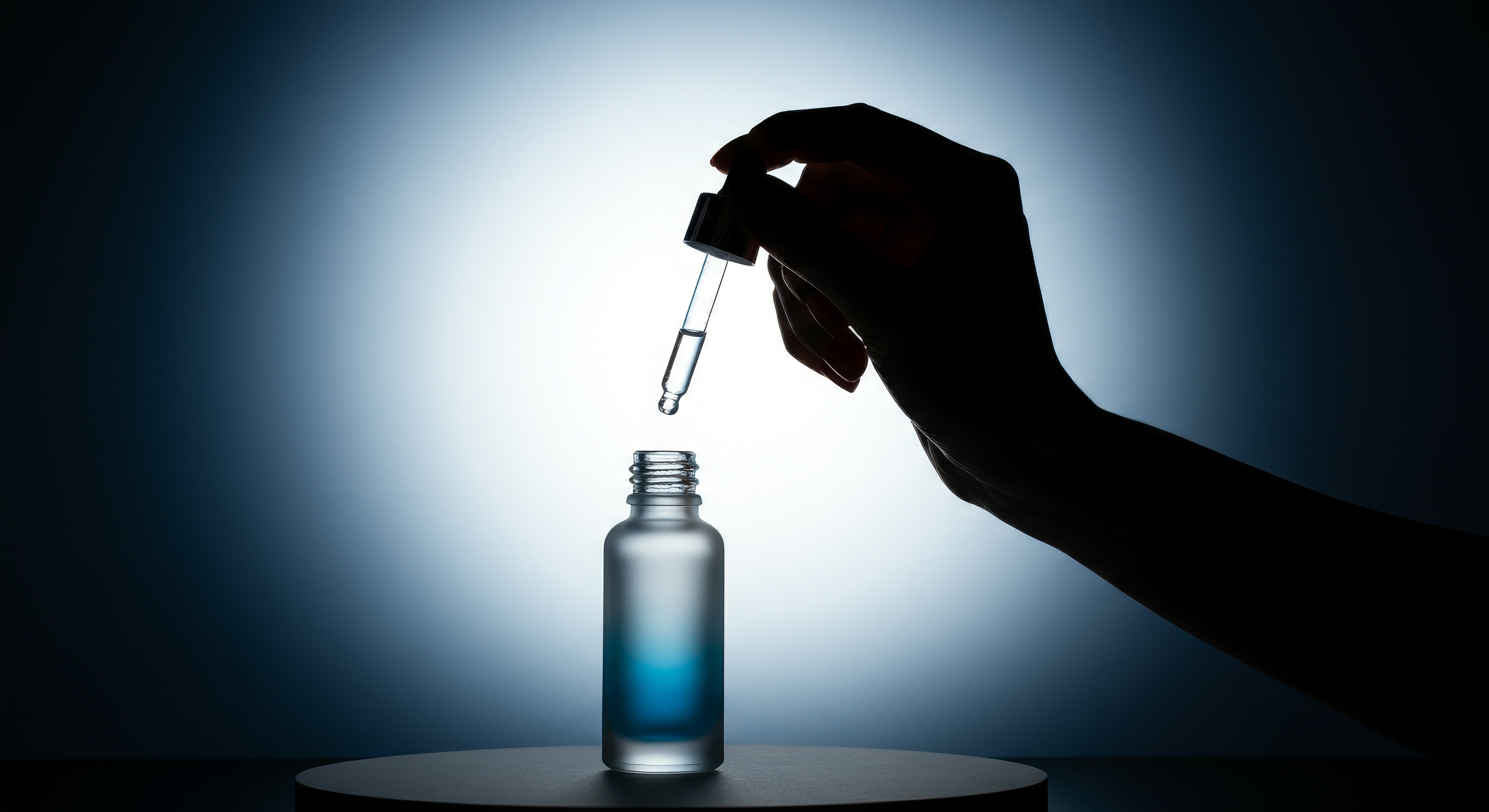 A dramatic silhouette of a hand holding a dropper, poised over an open, frosted glass bottle, with a single drop of liquid suspended. The high-contrast backlighting emphasizes the precision and delicate nature of the product. This image is ideal for showcasing serums, essential oils, medical drops, or highly concentrated beauty products, highlighting their efficacy and careful application. It would be a compelling visual for product pages on a **Liqua Premium Ecommerce template**, conveying a sense of quality and meticulous formulation.