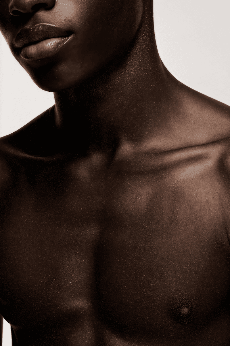 A close-up, cropped view of an individual's upper chest and neck, highlighting deep, rich skin tones with subtle contours and a healthy sheen. The focus is on the smooth texture of the skin and the defined lines of the collarbone. This image is ideal for promoting skincare, body care, or wellness products that emphasize hydration, natural glow, and healthy skin across all complexions. It would be a sophisticated and inclusive visual asset for a brand utilizing a **Liqua Premium Ecommerce template**.