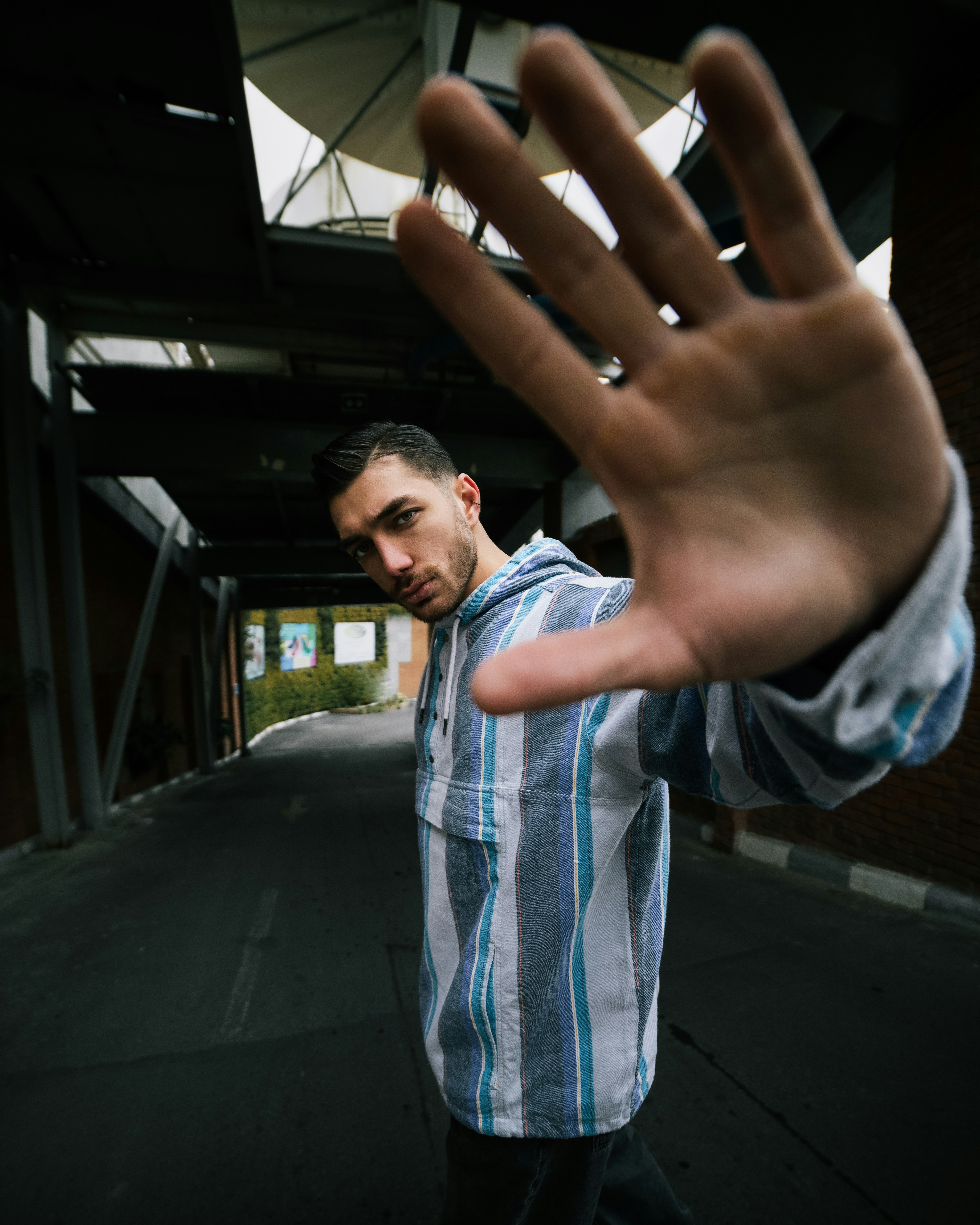 Man from behind in a black "FOR THE FUTURE" globe tee and shiny pants in a stylish cafe and clothing shop.