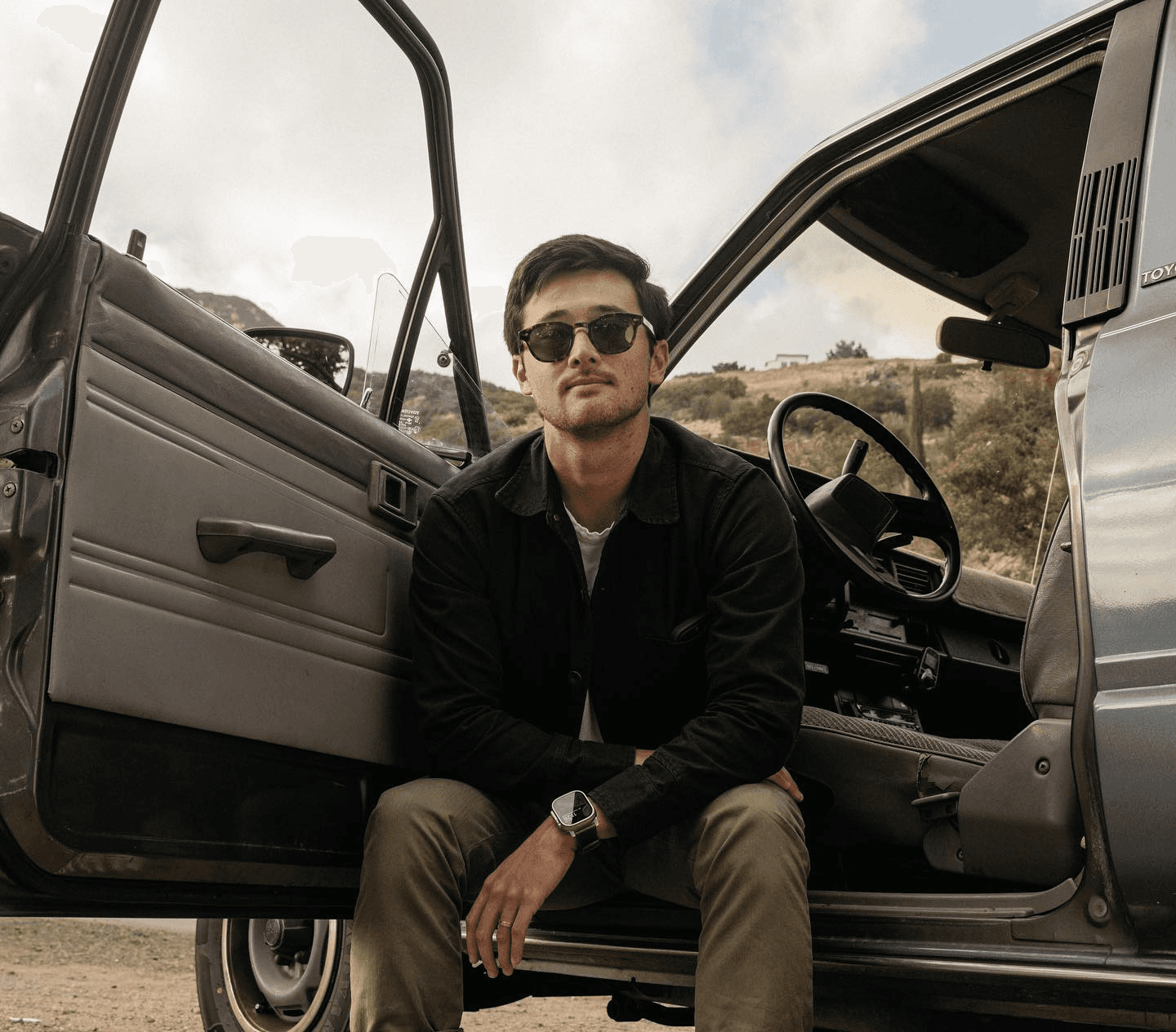 black jacket guy sitting in a car with door open